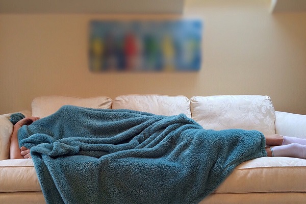 Човек спие на кауч, покриен преку глава