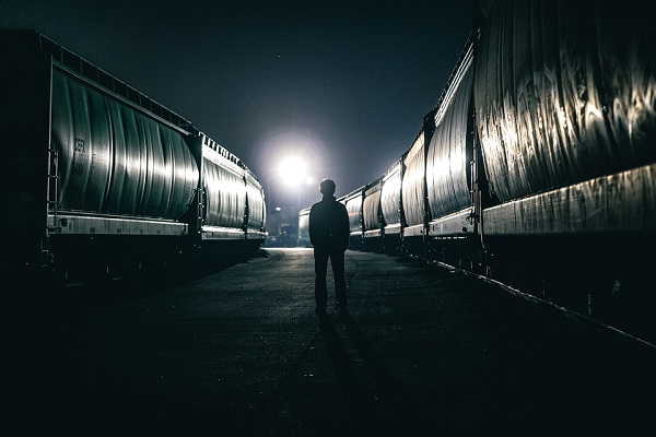 Човек стои помеѓу вагони сред ноќ