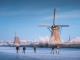 Прекрасна глетка од лизгачи на мраз покрај ветерници во холандско село