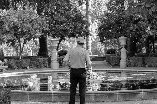 Возрасен човек свртен кон фонтана