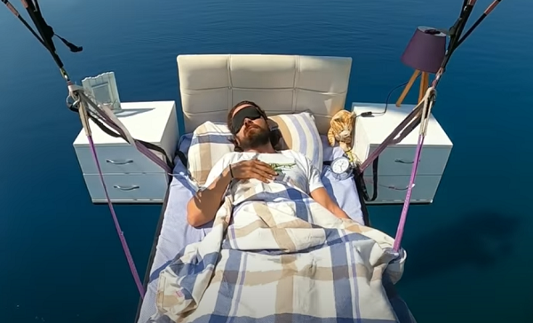 Параглајдерист леташе над Анталија лежејќи на кревет