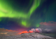 Прекрасна поларна светлина над вулкан што еруптира на Исланд